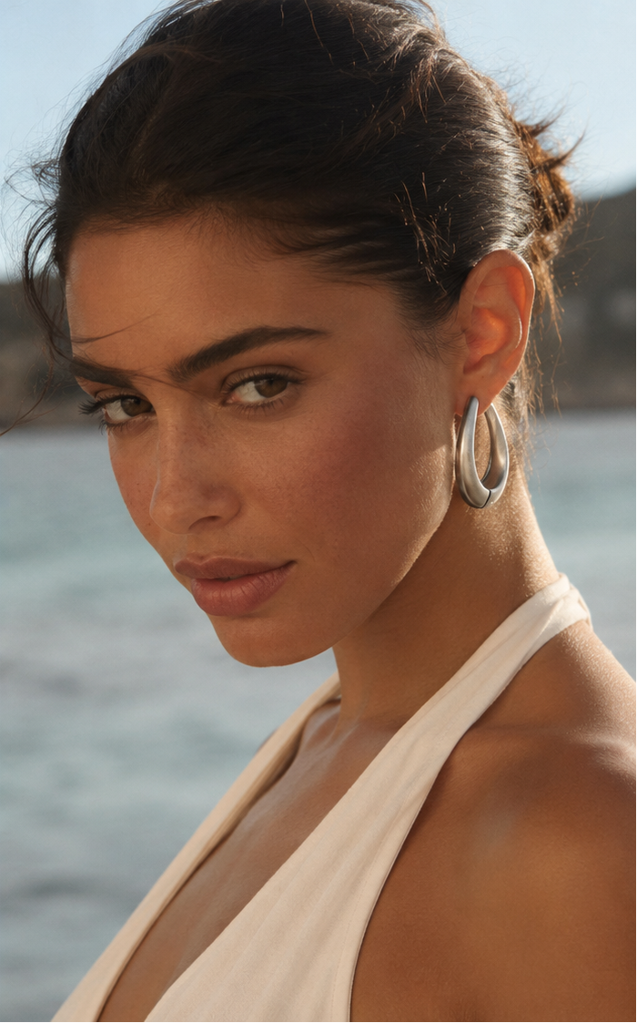 Femme portant des boucles d’oreilles goutte sculptée couleur argent