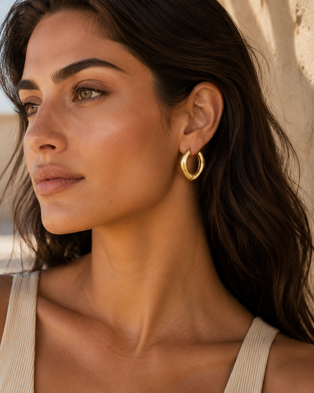 Boucles d’oreilles anneau géométrique dorées Lumé portées par une femme