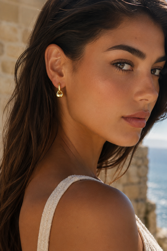 Femme portant les boucles d’oreilles dorées nouées Lumé