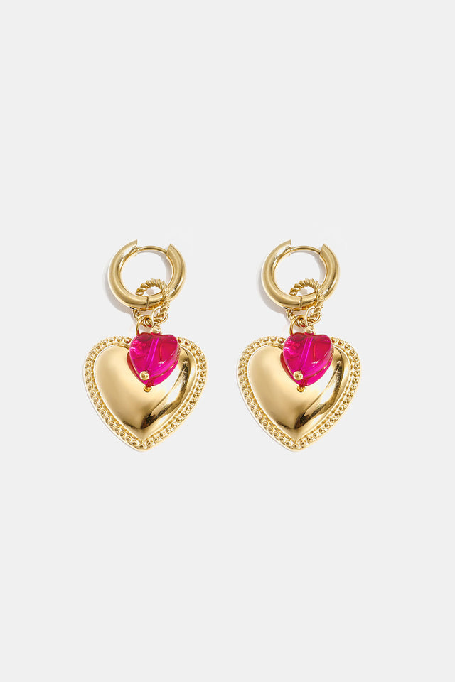 Boucles d’oreilles pendantes cœur doré et cristal fuchsia Lumé sur fond clair