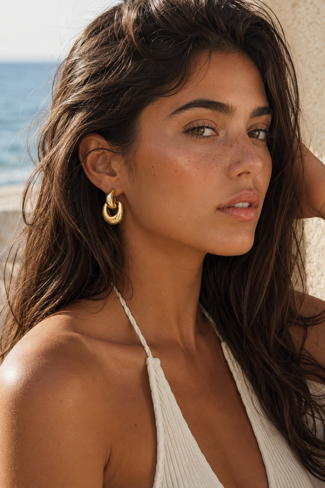 Femme portant les boucles d’oreilles dorées entrelacées Lumé